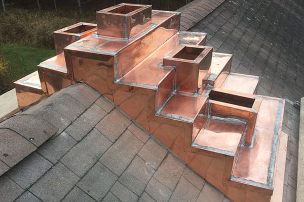 Copper roofing installation on a residential structure, showcasing intricate details and craftsmanship, complementing Twin Roofing's metal roofing services in Massachusetts and New Hampshire.